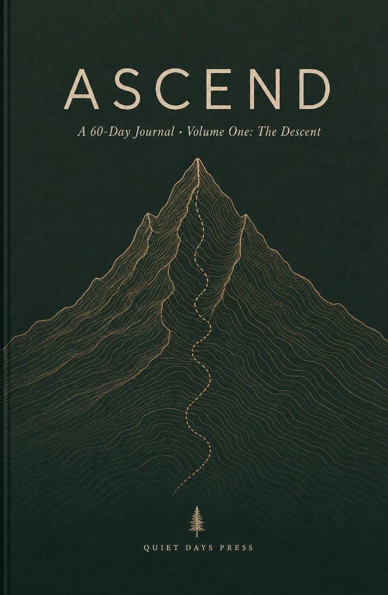Ascend Volume One paperback cover: the word ASCEND in letterspaced brass serif capitals on a deep forest-green field, above a brass line-drawn mountain with a dotted trail to the summit, the line 'A 60-Day Journal · Volume One: The Descent', and the Quiet Days Press imprint at the foot.